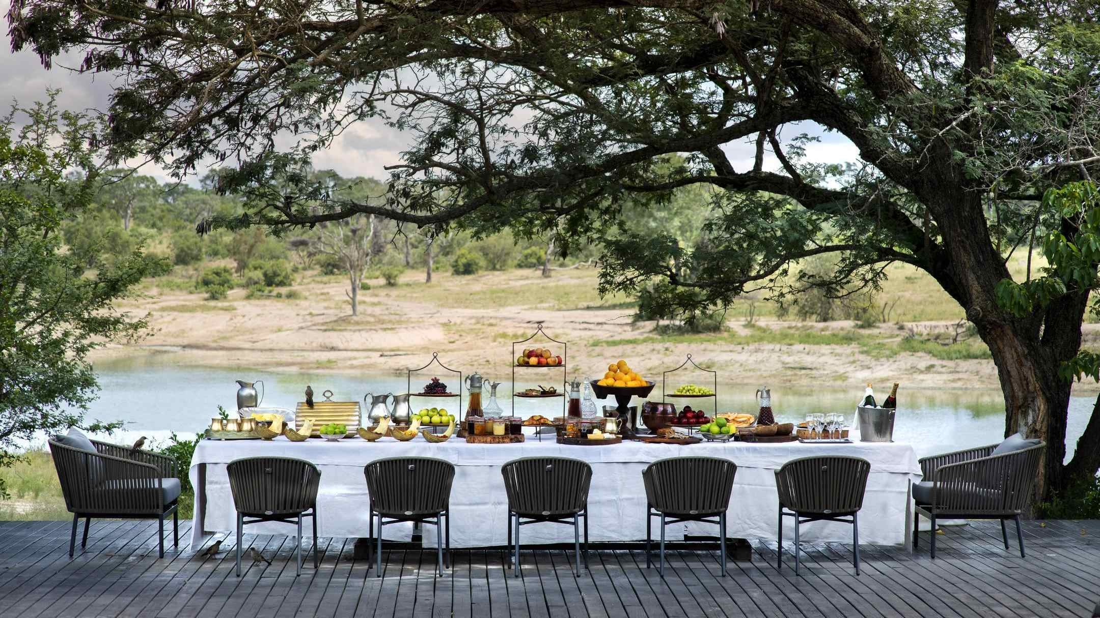 Outdoor dining at Chitwa Chitwa featuring a long table overlooking the bush.