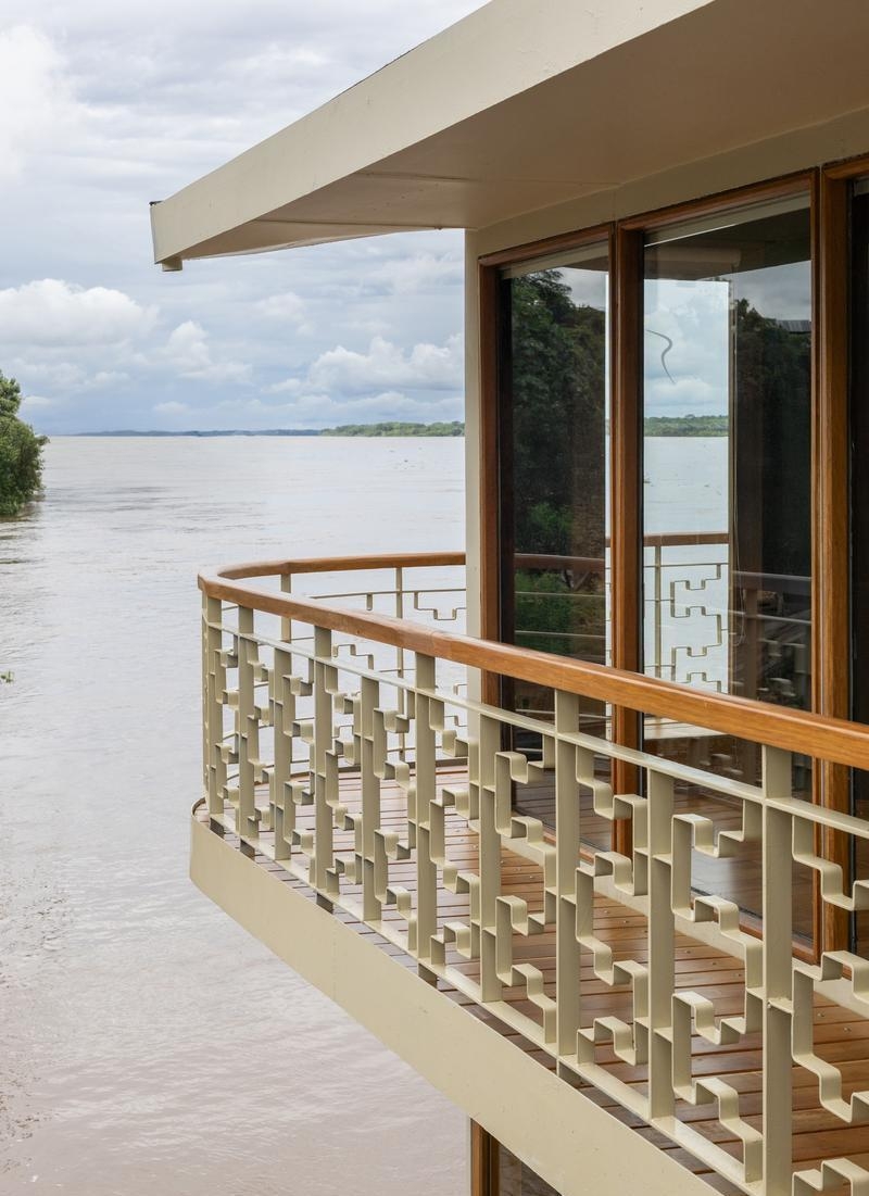 A modern geometric metal railing on Delfin I's deck with a wide river and cloudy sky in the background.