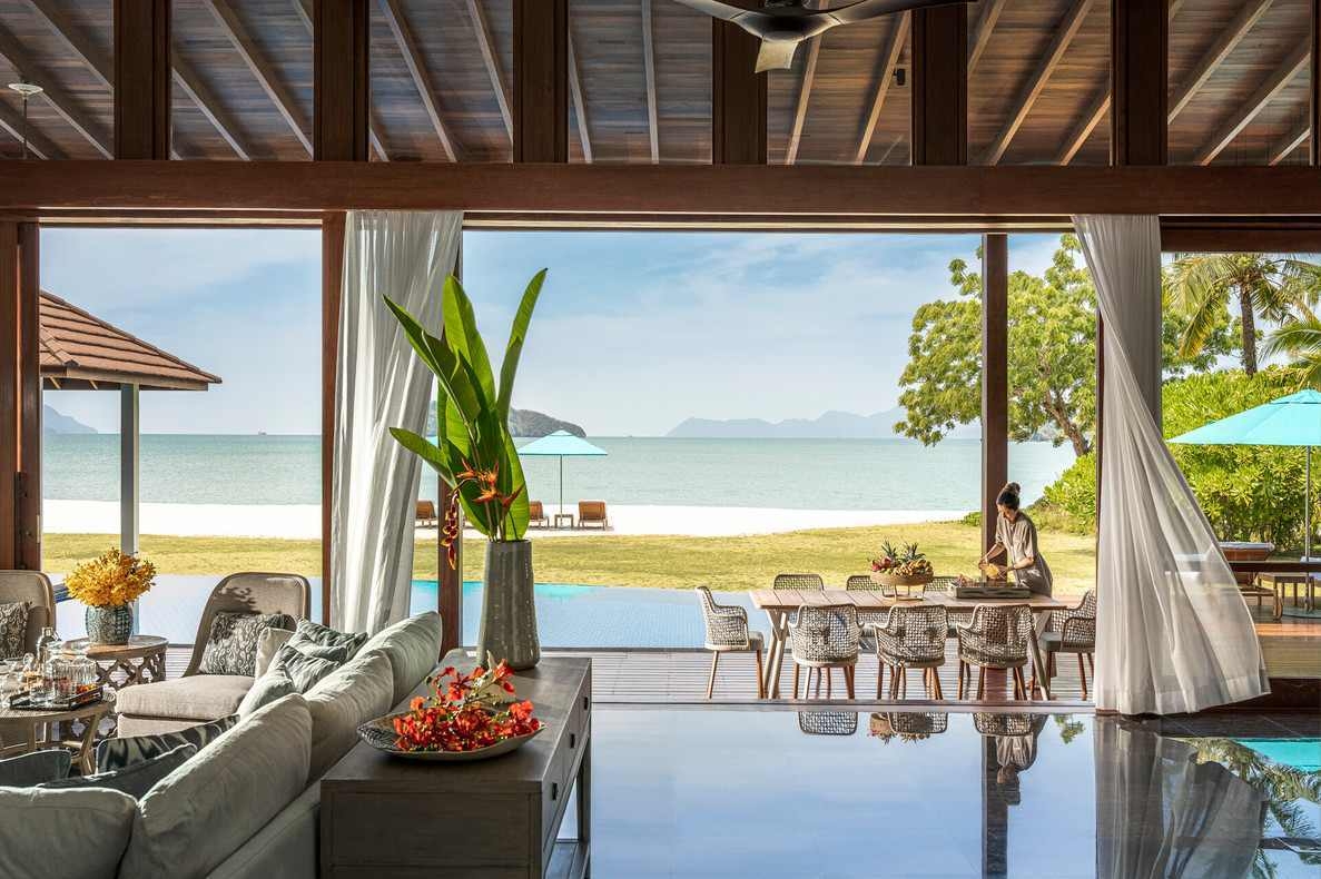 Inside a beachfront villa looking out to a private infinity pool, white sand beach and blue ocean waters.