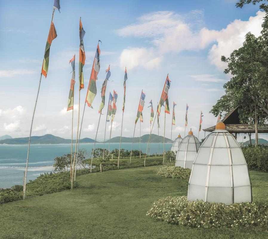 Grassy lawn with tall flags and white decorative pods overlooking the sea.