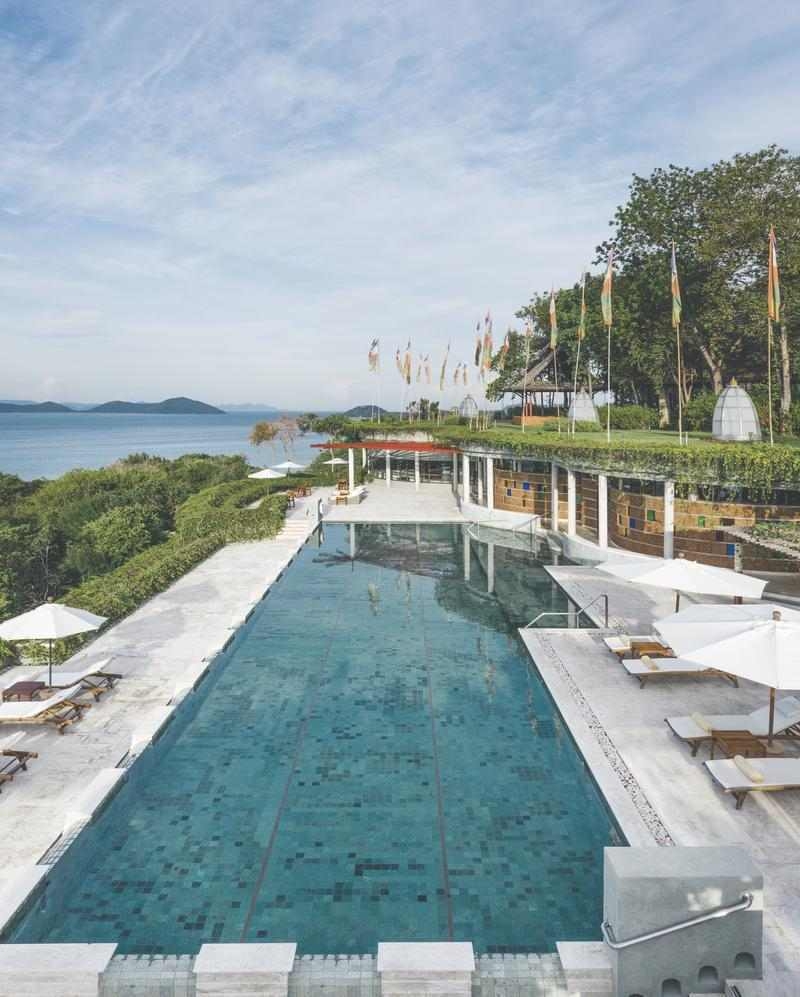 A swimming pool with lounge chairs and umbrellas overlooking the sea.