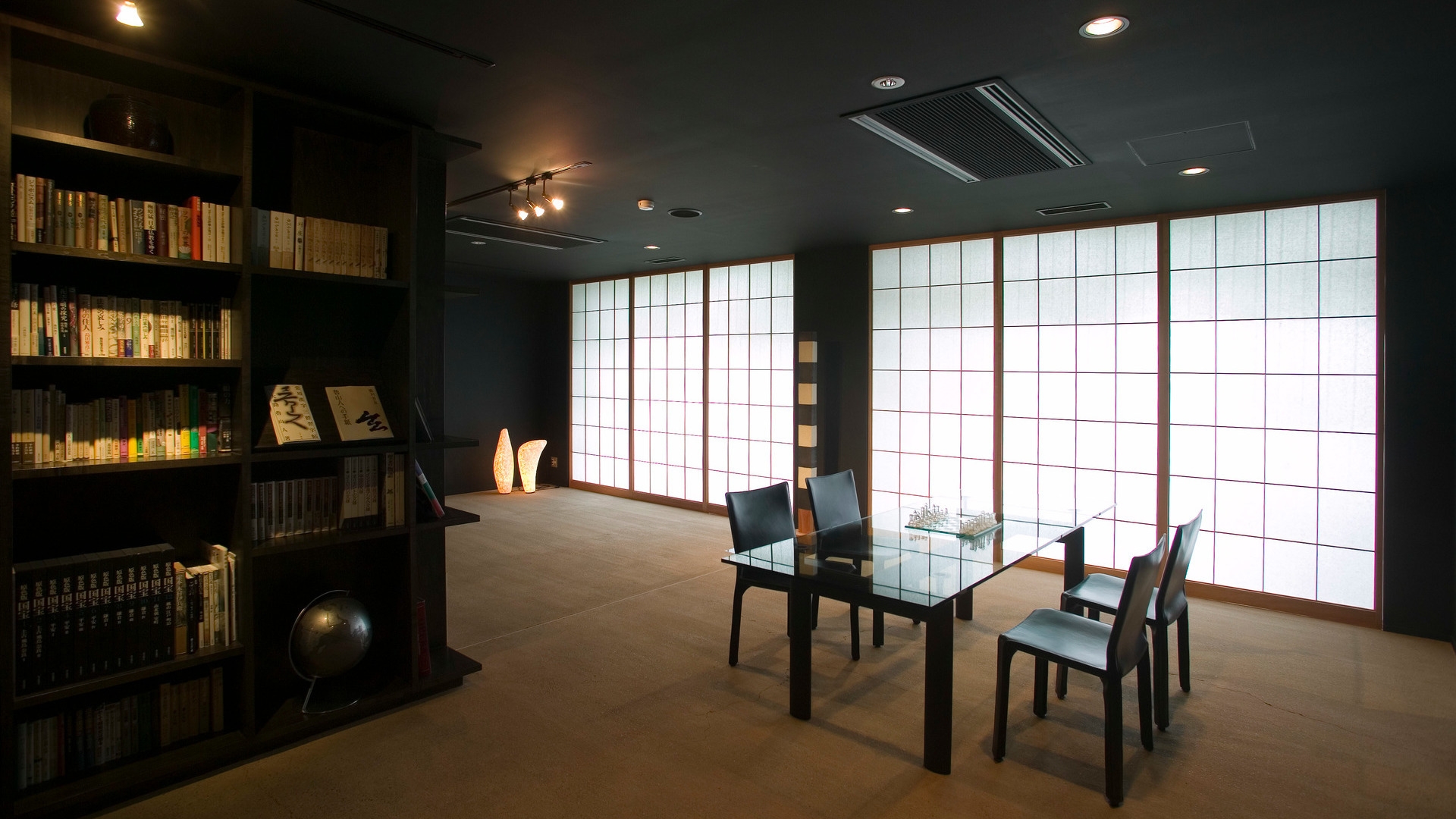 Quiet library at Beniya Mukayu with bookshelves, a glass table, and glowing shoji screen windows.