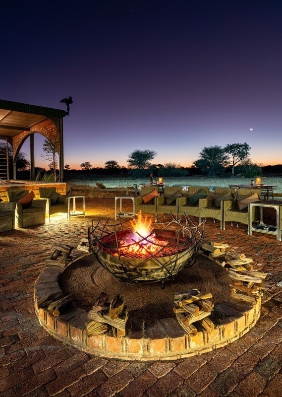 Lit firepit with camp chair circle around it at night at Okonjima Plains Camp