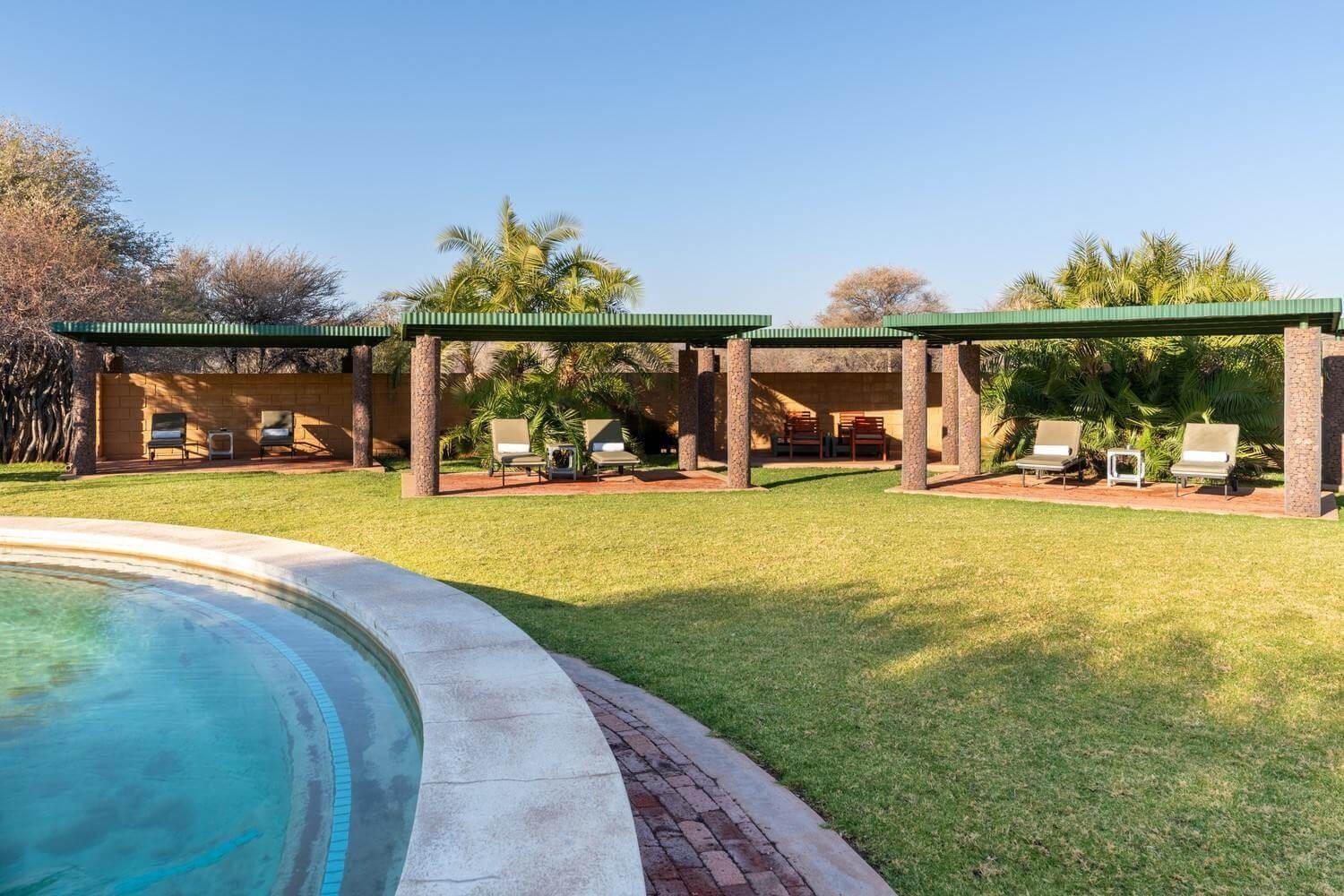 Outdoor pool area with sunloungers at Okonjima Plains Camp