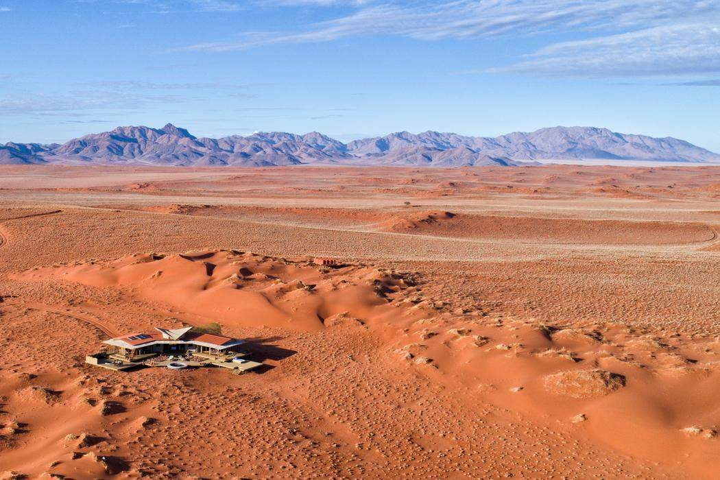 High-angle view of Wolwedans surrounded by rolling red dunes and distant mountains.