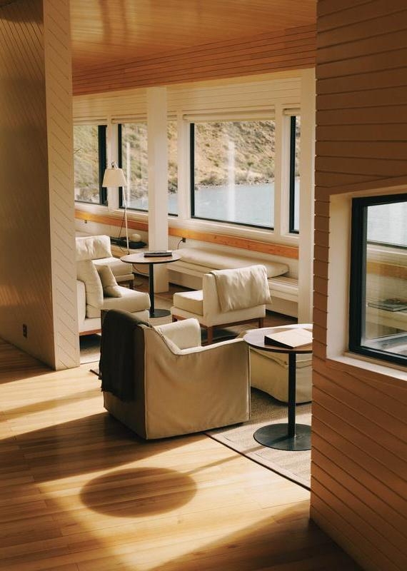 Bright lounge room at Explora Patagonia with white couches and large windows overlooking a turquoise lake.