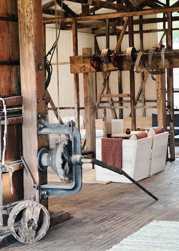 Rustic timber building interior at Explora Patagonia with exposed wooden framing and an old metal winch.