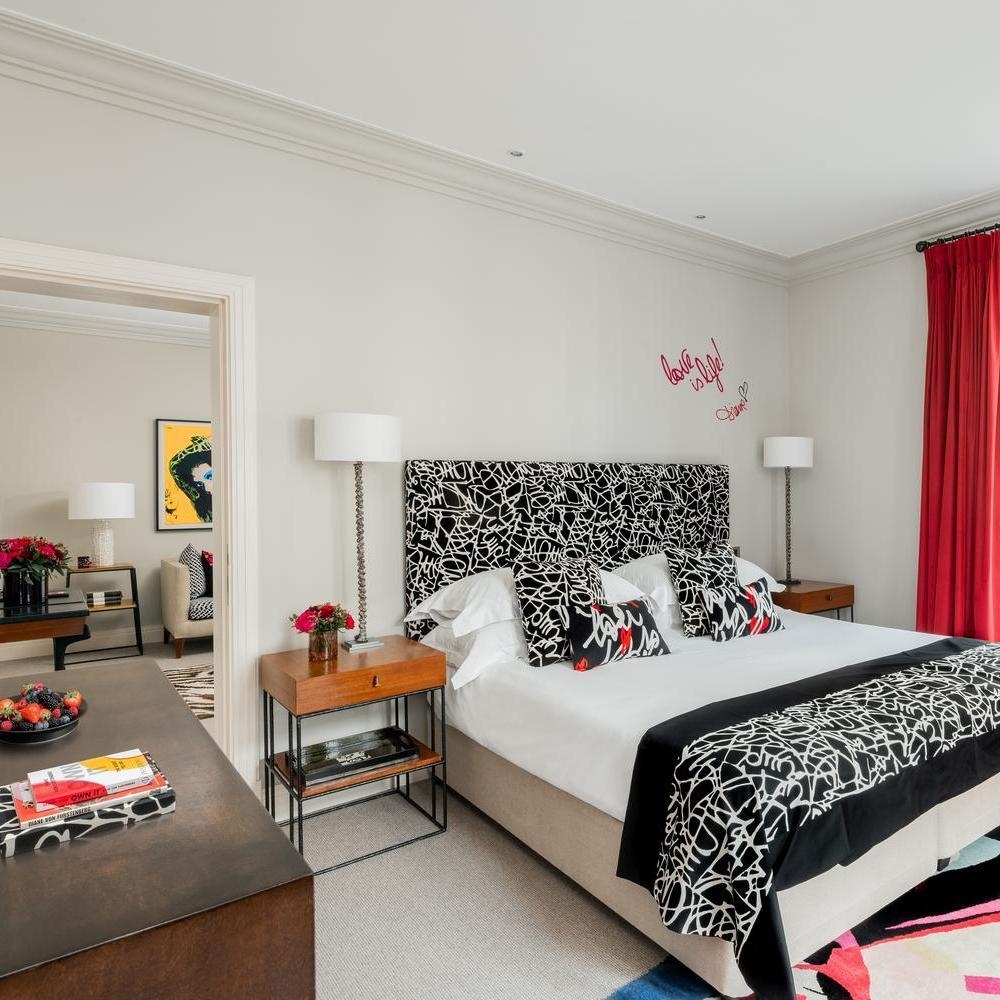 Bedroom in the Diane von Furstenberg suite at hotel amigo in belgium with patterned bedding and red curtains.