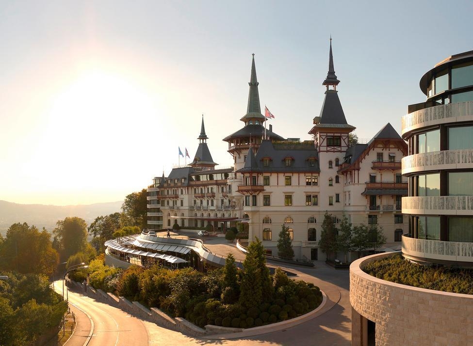 The Dolder Grand hotel in Zurich with its iconic spires and modern architecture at sunrise.