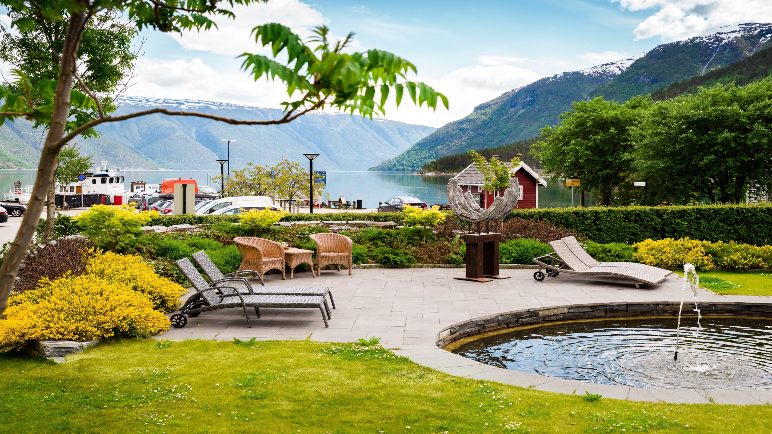 Luxury patio with chairs and fountain overlooking a fjord and mountains.