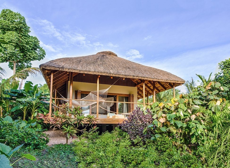 A thatched wooden villa surrounded by greenery at Zuri Zanzibar