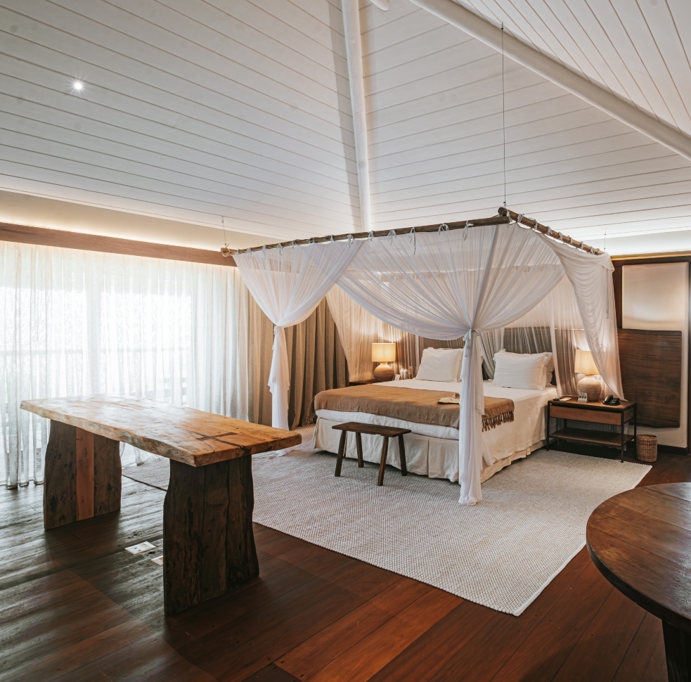 Elegant bedroom with canopy bed, rustic wooden furniture, and sheer curtains.