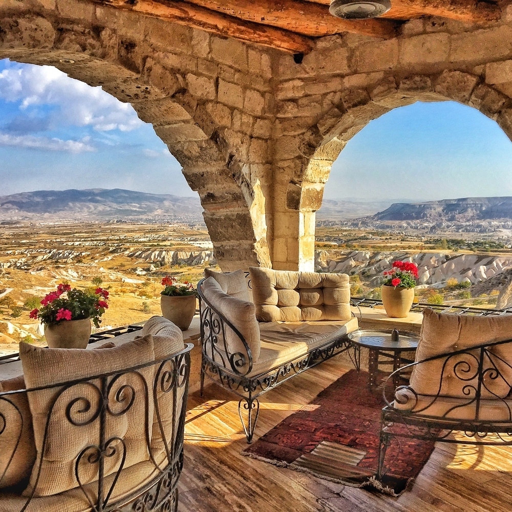 Stone arch terrace with plush seating and flowers overlooking the valley at the Museum Hotel in Turkey.