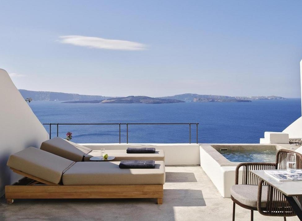 Terrace at Andronis luxury suites with two sun loungers, a small table with an apple, a plunge pool, and sea views.