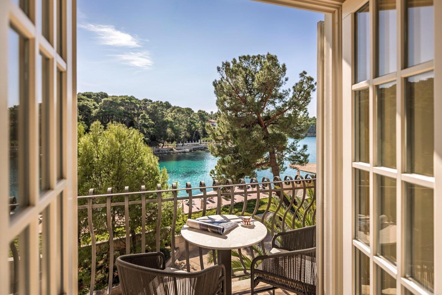 Window opening onto a small balcony with a view over the sea and trees at Boutique Hotel Alhambra, Croatia