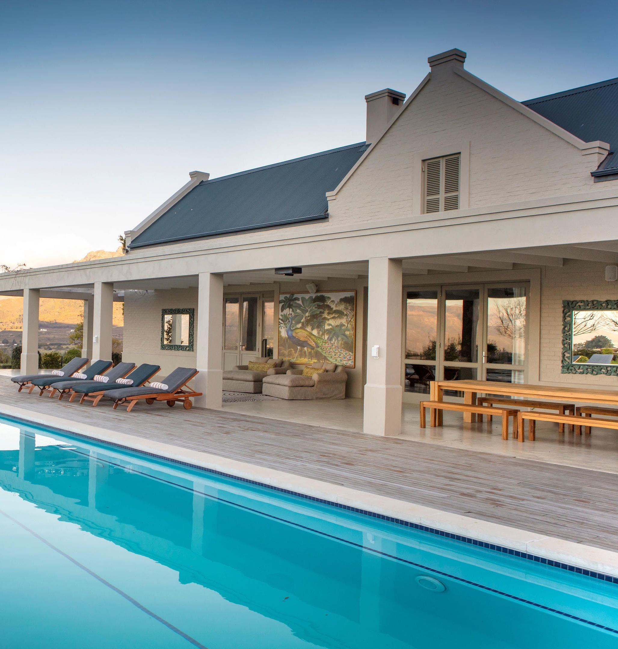 Luxury house with a pool, patio, and mountain view at dusk.