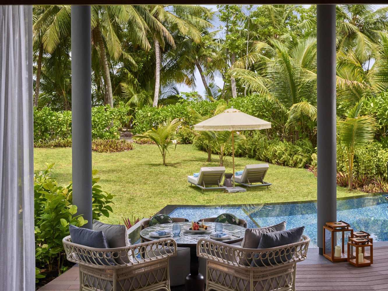 The outdoor area of a villa at Waldorf Astoria Seychelles Platte Island, featuring a pool and sun loungers in a garden.