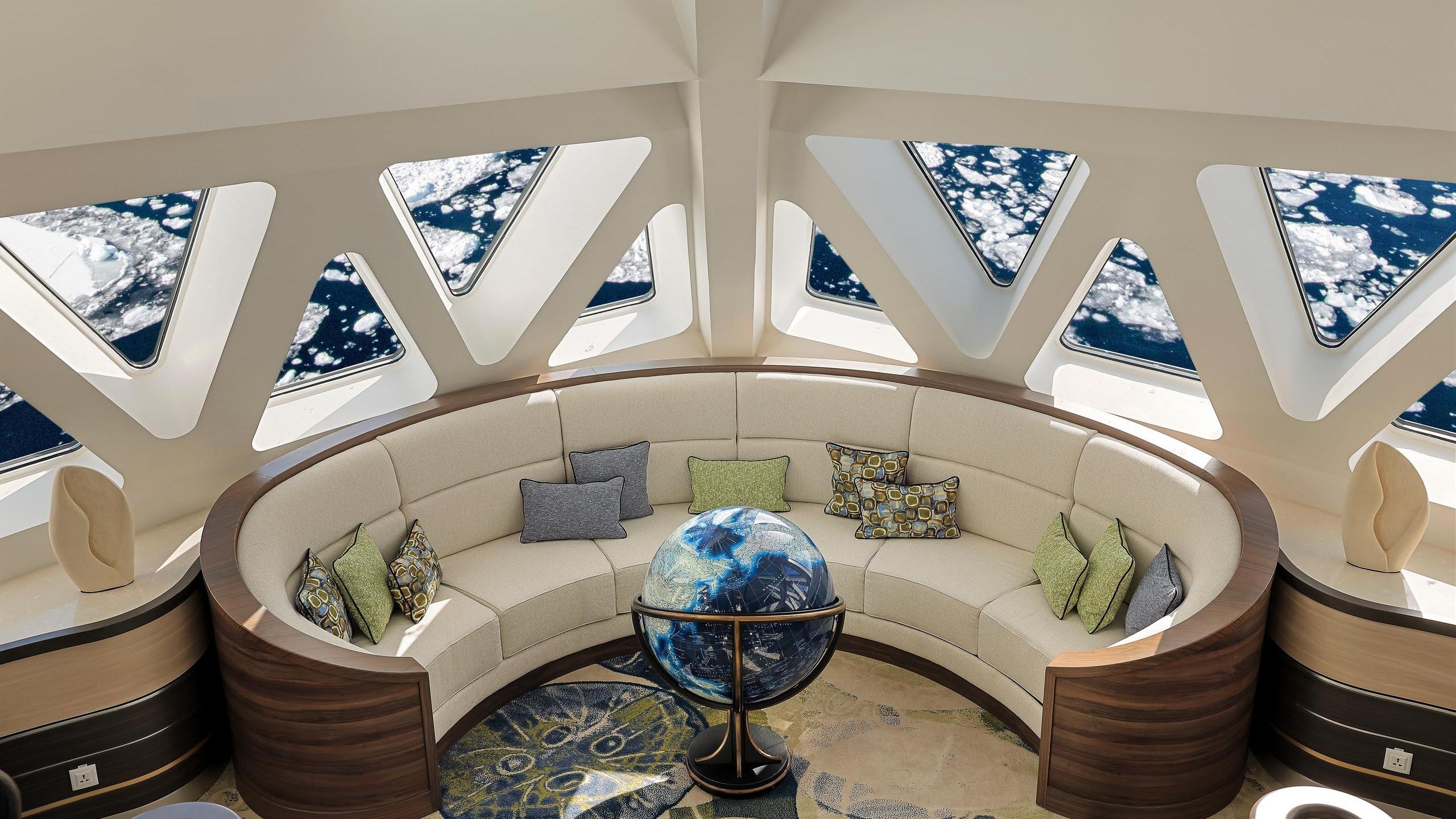 A curved sofa and globe sit beneath triangular windows viewing sea ice on the Douglas Mawson.