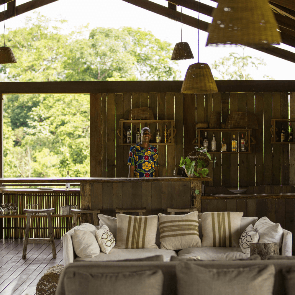 Open-air bar and lounge area with a smiling man standing behind the bar