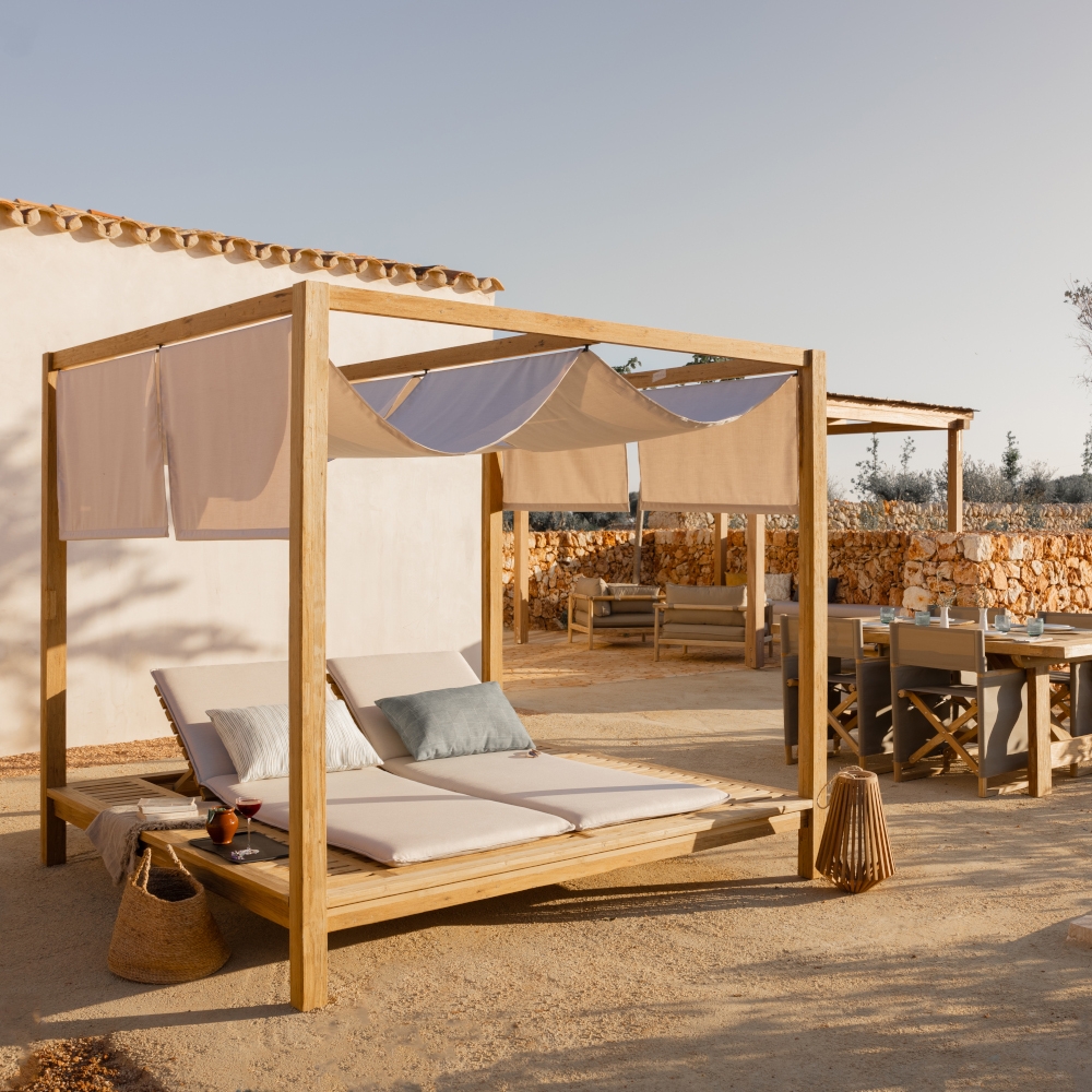 Luxury outdoor daybed and dining terrace at Son Vell in Balearic Islands Spain under bright Mediterranean sunlight.
