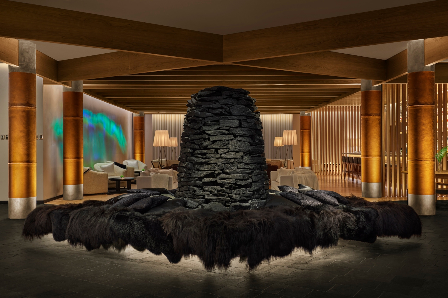 Hotel lobby with dim, warm lighting and a huge black volcanic stone sculpture in the centre of the room.