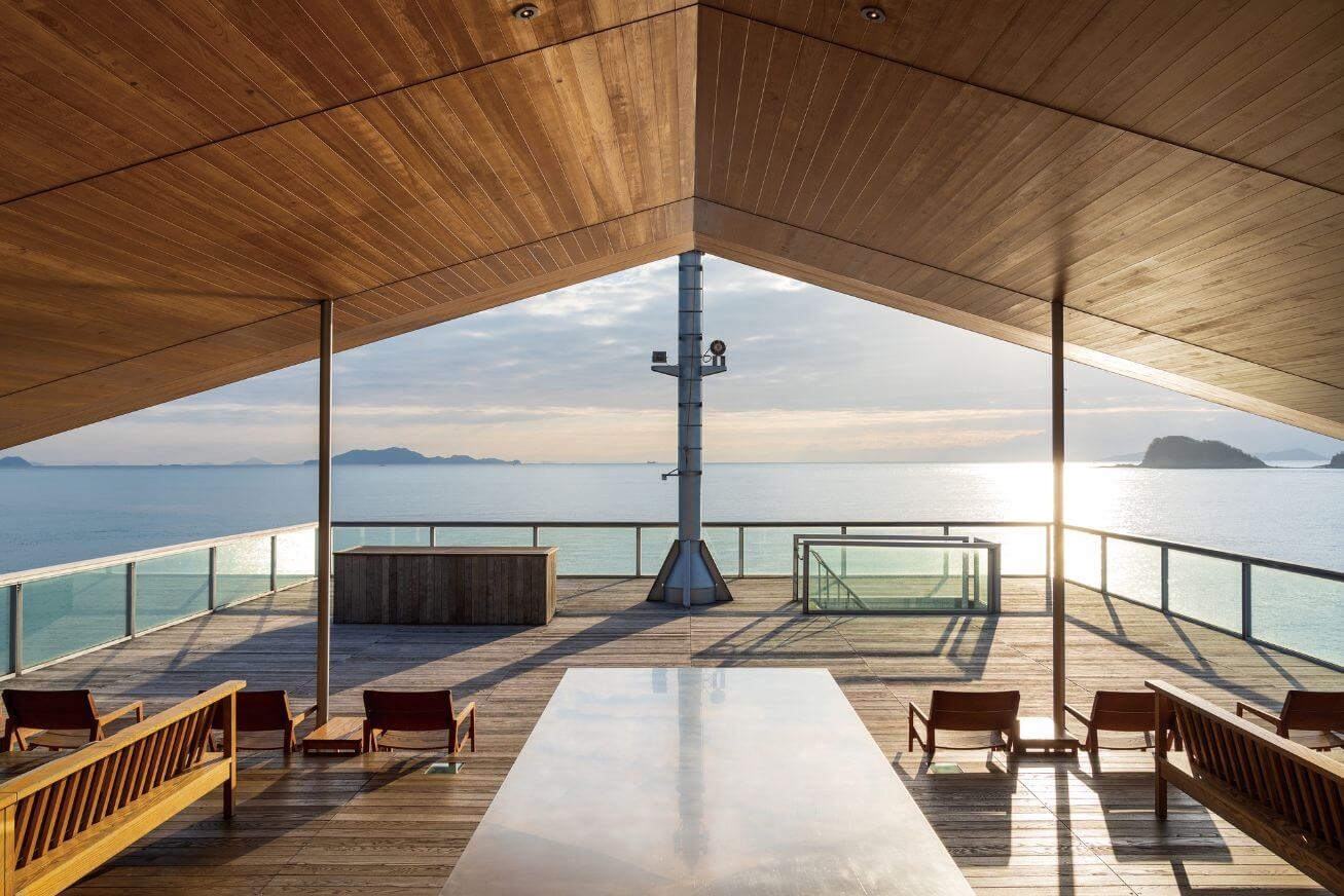 Open deck on a ship with a slanted wooden roof and various tables and chairs