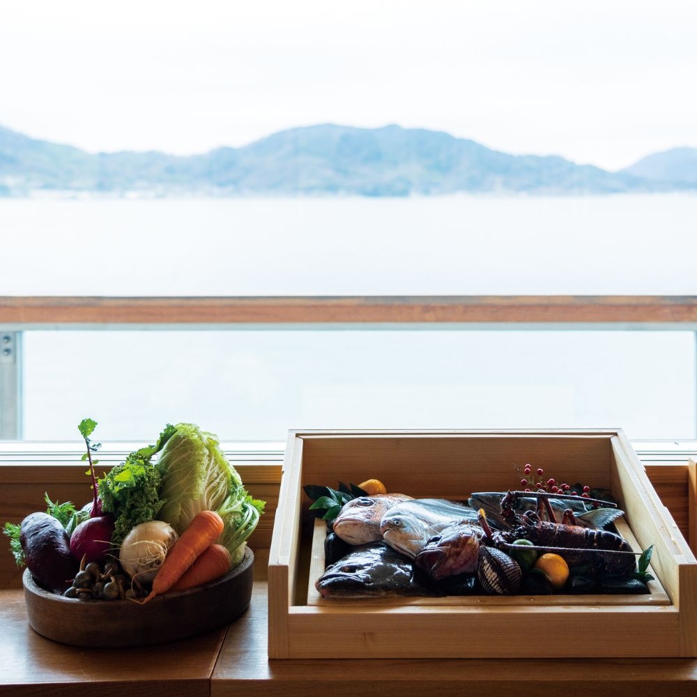 Close-up of fresh vegetables and seafood with the sea and mountains in the background