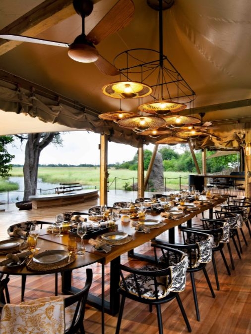 A long table set for dinner on a covered wooden deck