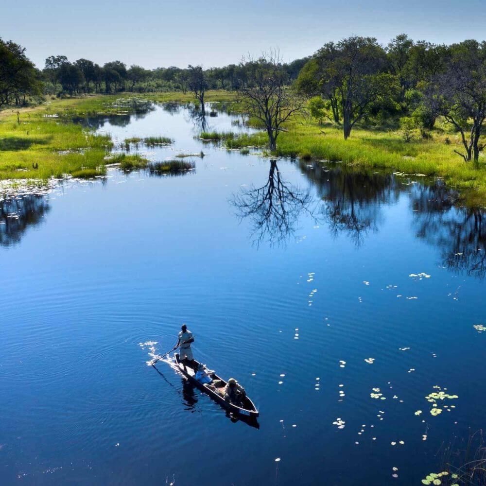 Three people in a mokoro on the Khwai River