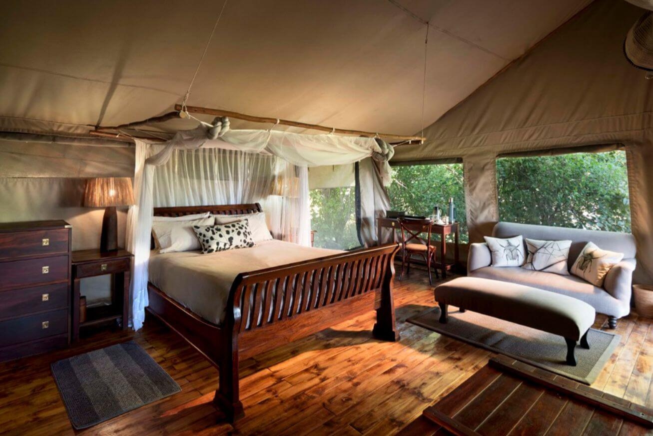 Wooden bed with mosquito netting in a luxury safari tent