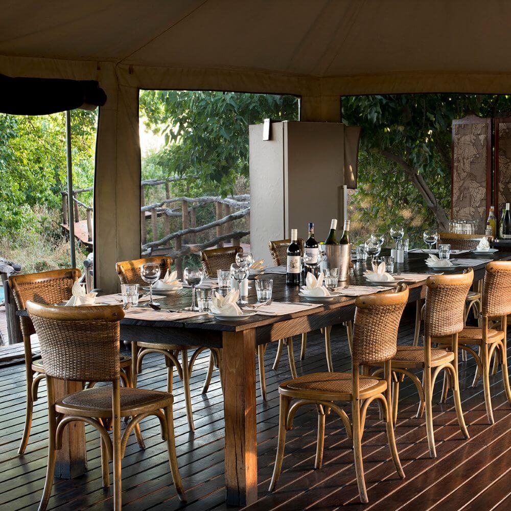 A long table set for dinner with several bottles of wine