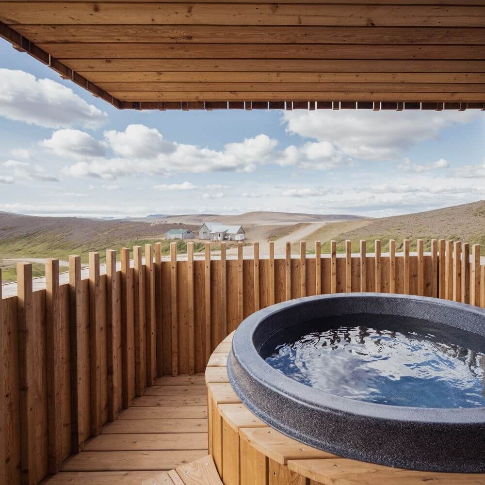 A wooden balcony with a bathtub overlooking the mountains