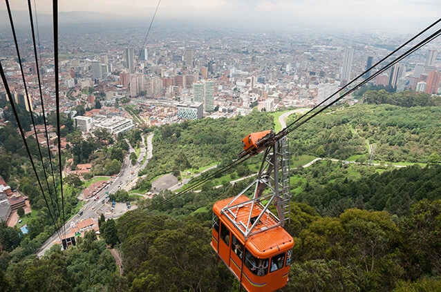n orange cable car descends towards the large, sprawling cityscape of Bogotá below, offering scenic views as part of Luxury Colombia Holidays.