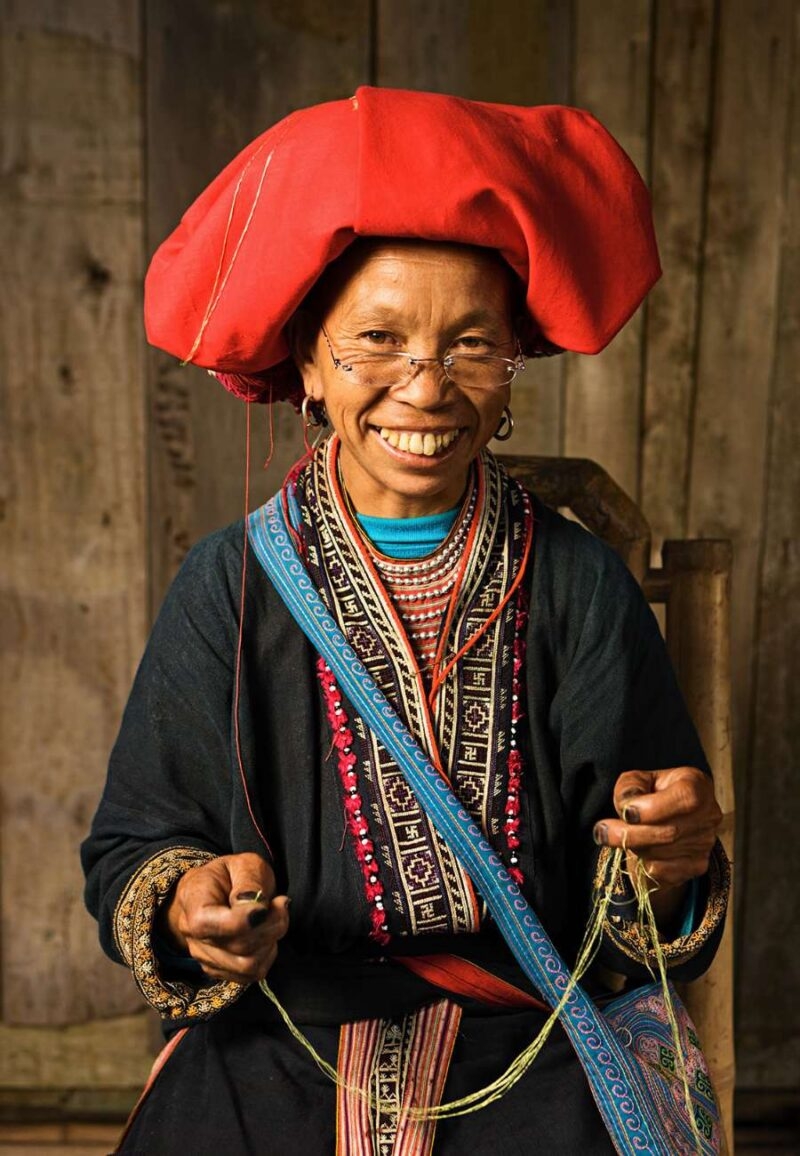 Woman in a red headdress and traditional attire on luxury Southeast Asia tours.