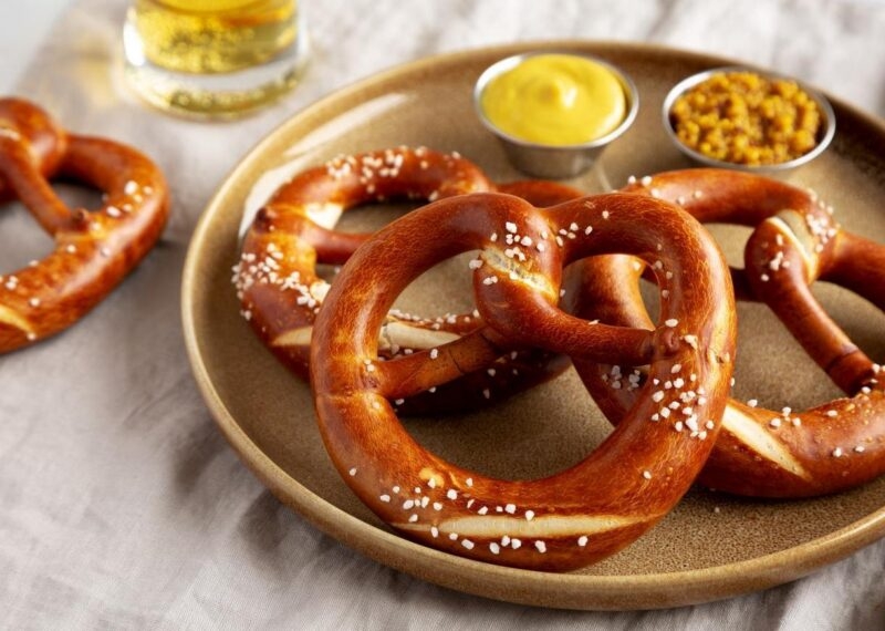 Plate with salted pretzels and mustard dips on a table.