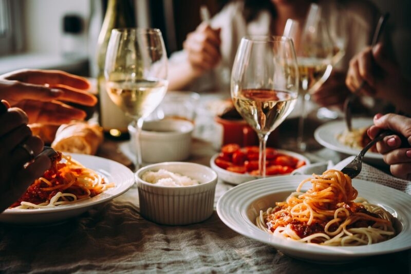 People enjoying an Italian meal of pasta with wine