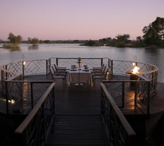 Outdoor deck at Thorntree River Lodge featuring a dining table and sweeping views of the Zambezi River.