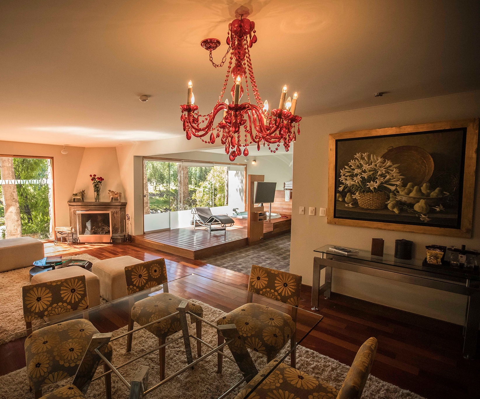 Elegant living room interior with red chandelier, hardwood floors, and large window with garden view.