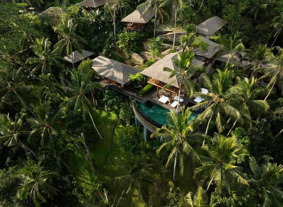 Aerial view of Como Shambhala's thatched-roof villas and pools surrounded by a lush tropical jungle forest.