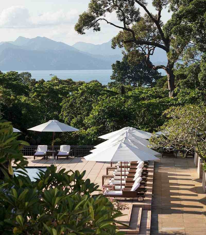 The Data's pool deck with white umbrellas and lounge chairs overlooking the sea and mountains.