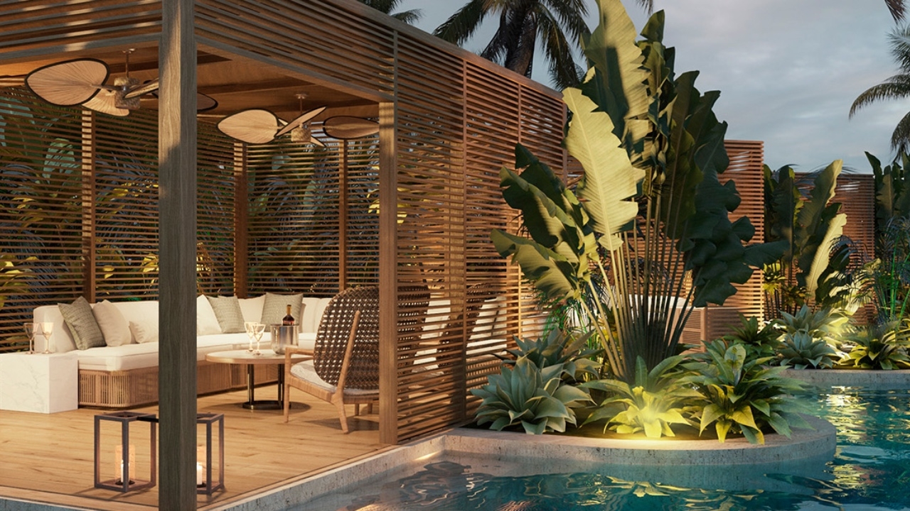 Outdoor patio with seating by a pool surrounded by tropical plants at dusk.