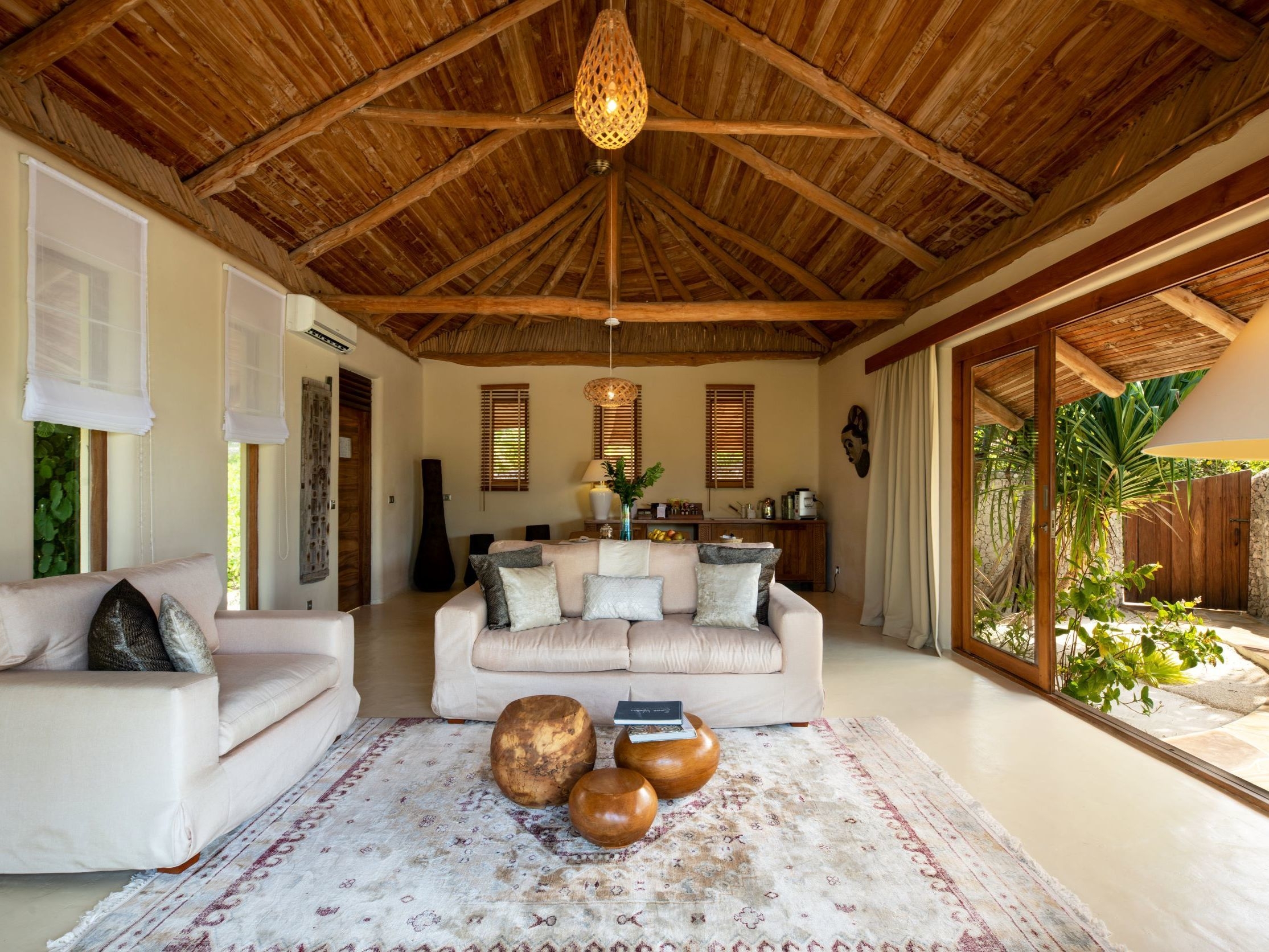 Spacious living room with a vaulted bamboo ceiling, plush sofas, and tropical outdoor views.