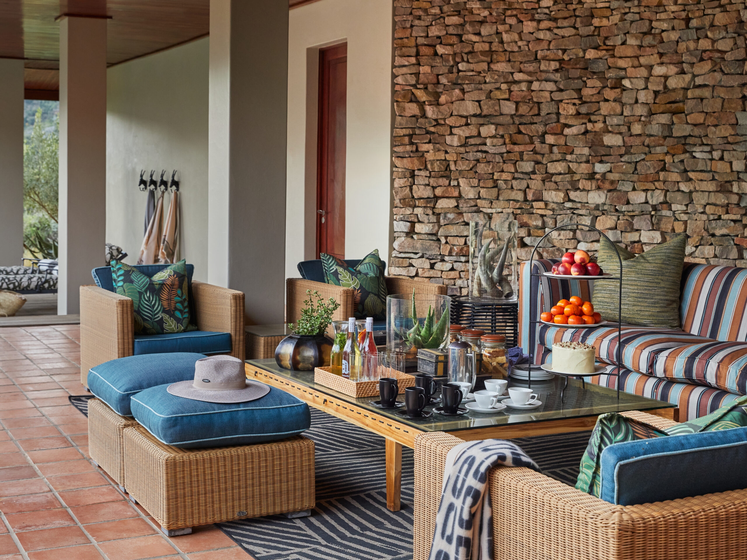 Cozy outdoor patio seating area with wicker furniture, colorful cushions, and a stone wall.