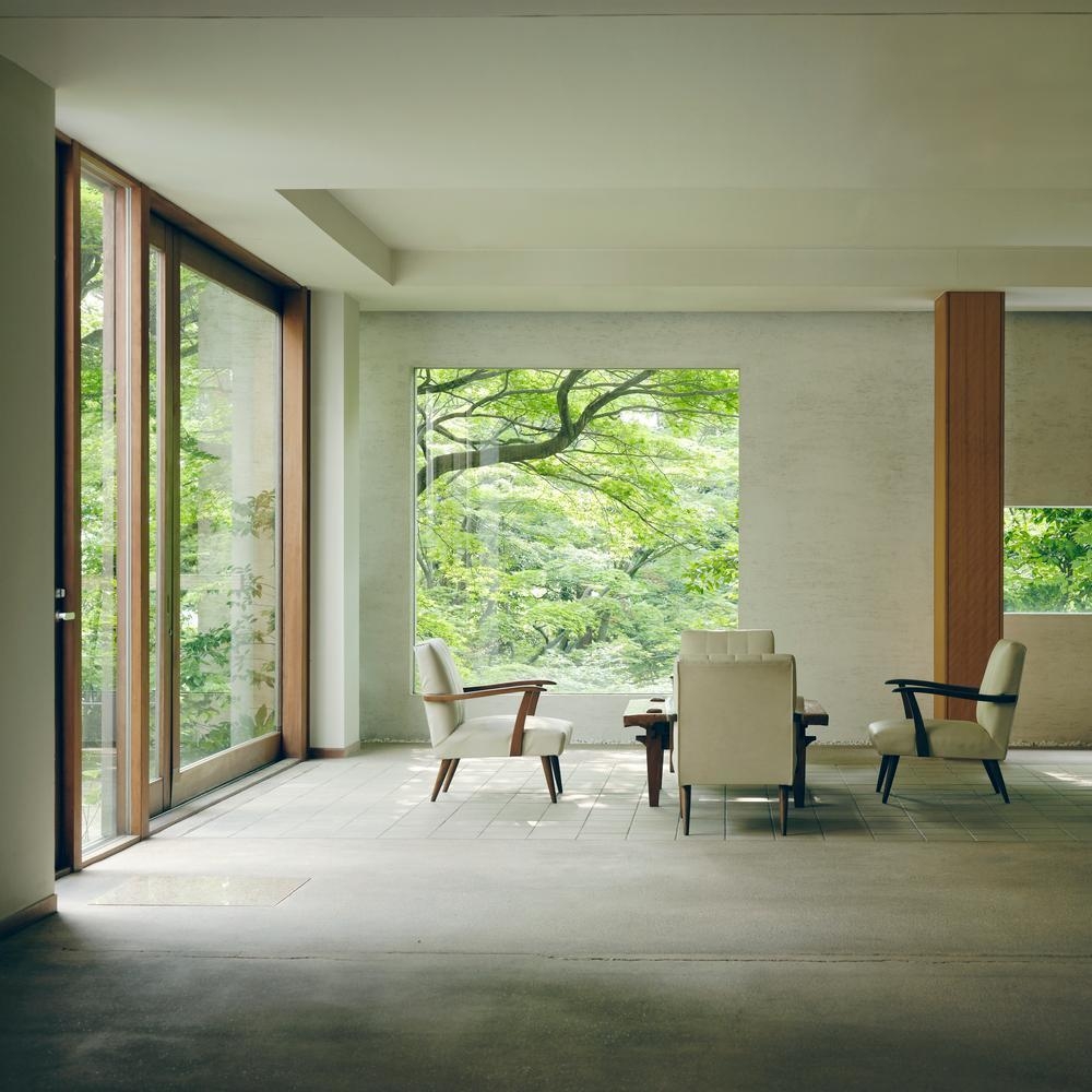 Minimalist lobby lounge at Beniya Mukayu with white chairs and expansive forest views through large glass walls.