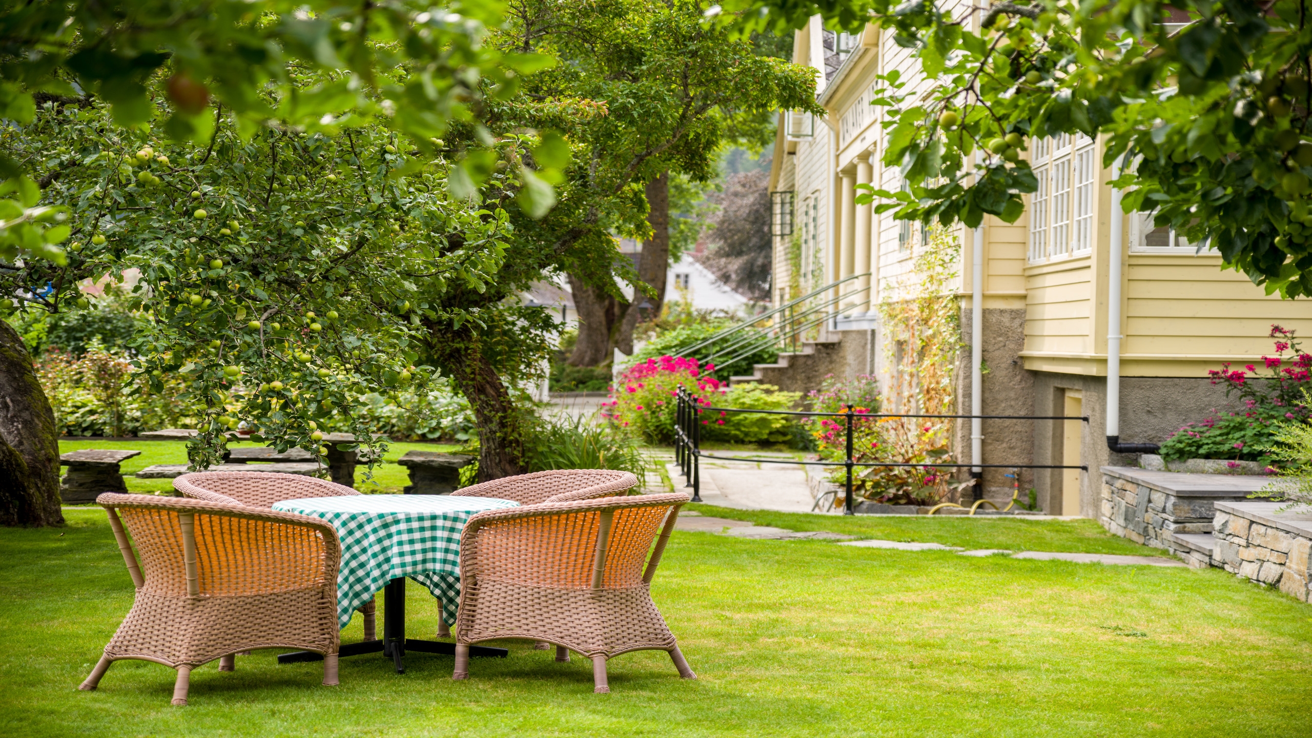 Outdoor garden seating with a table and chairs on lush grass near a classic house facade.