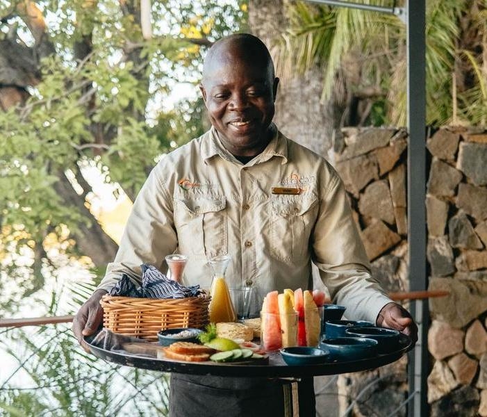 A man holding a platter of food at Thorntree River Lodge.