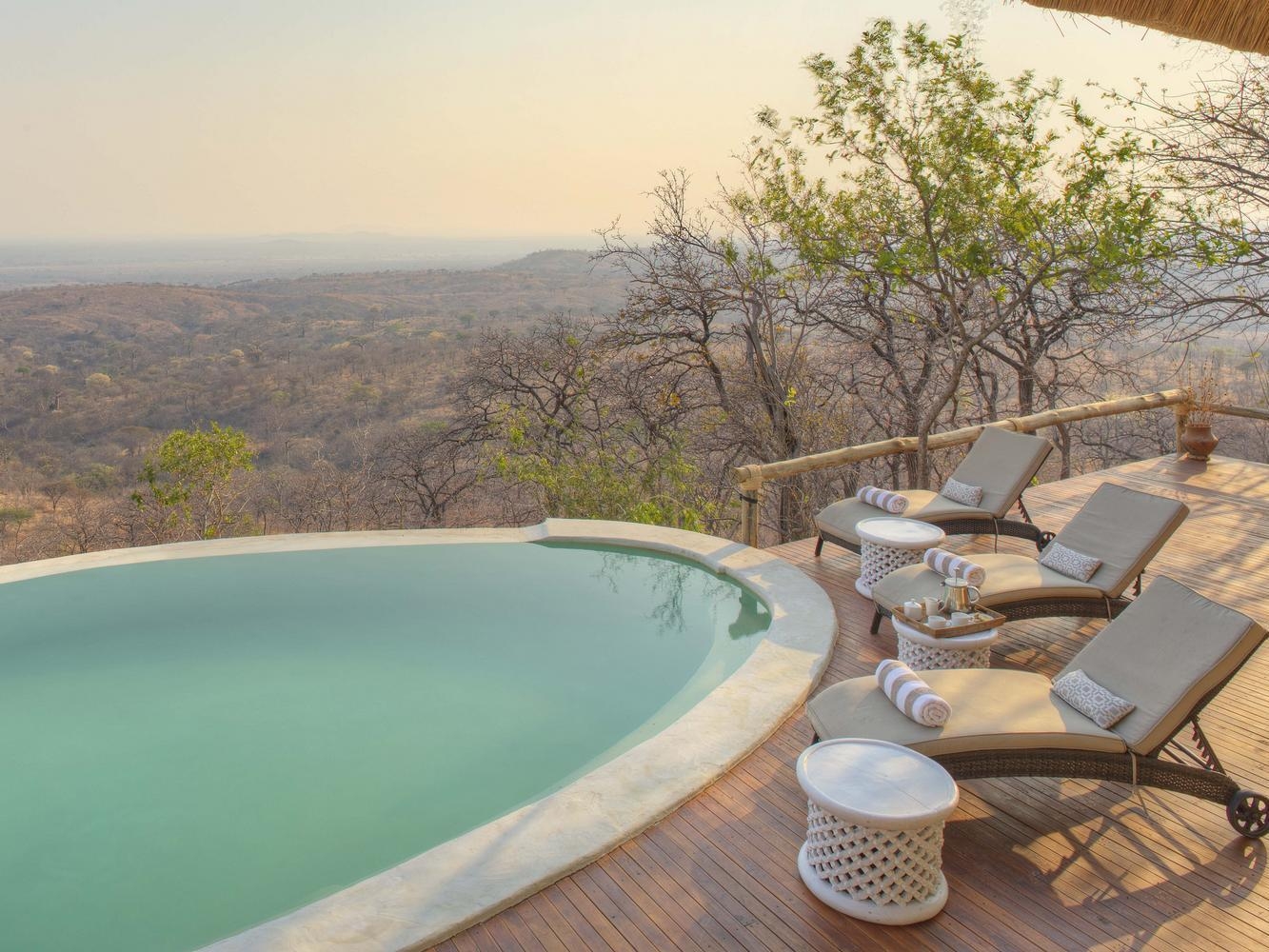 A swimming pool of a private room at Ikuka Safari Camp, featuring a terrace with sun loungers. The swimming pool overlooks the bush.