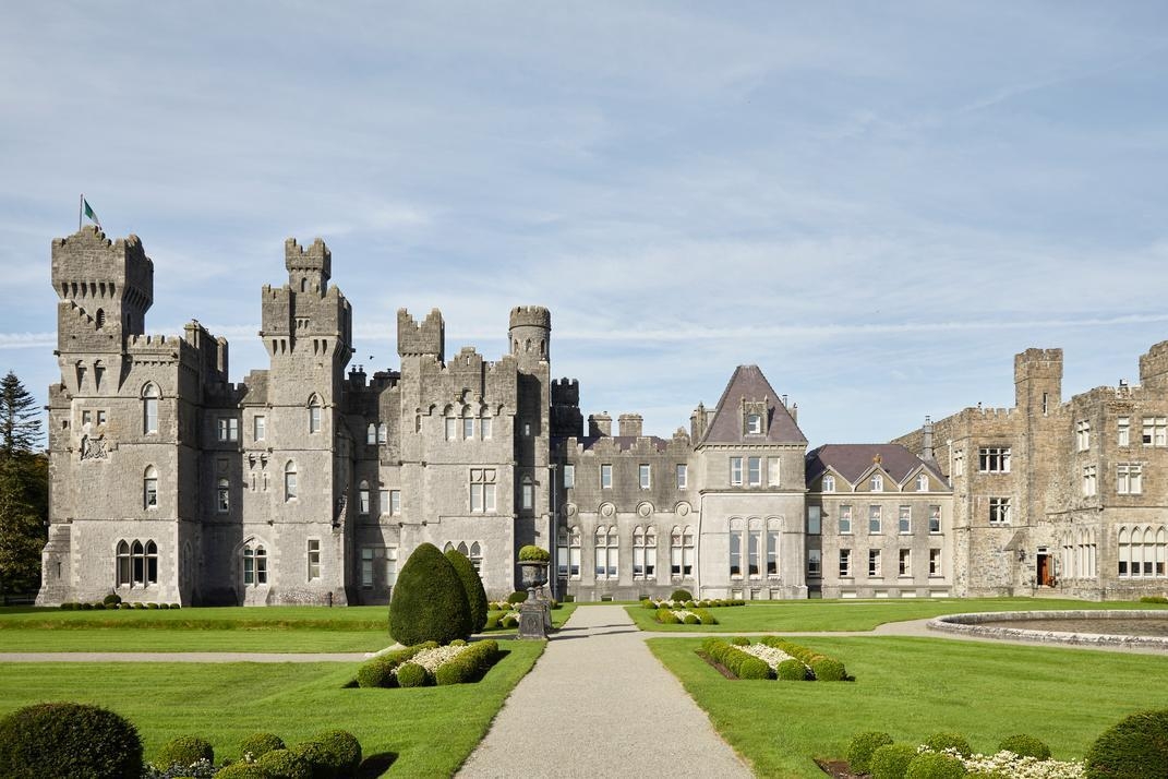 The exterior of Ashford Castle in Ireland with gardens in front