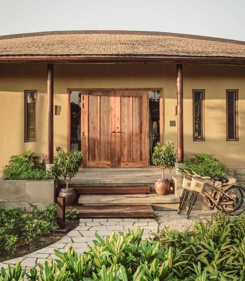 The wooden door entrance of a villa at Namia River Retreat with bicycles parked nearby.