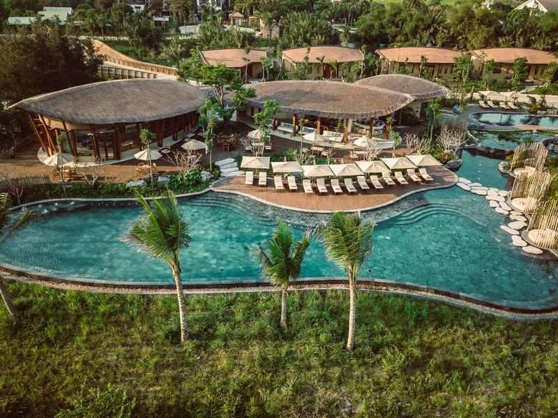 Aerial view of Namia River Retreat's lagoon swimming pool, sun loungers and tropical architecture.